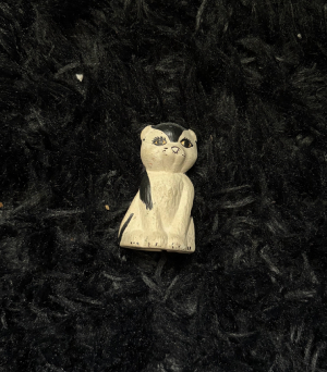 a ceramic black and white cat on a fluffy rug